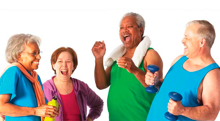 Da esquerda para a direita: duas idosas e dois idosos dão risadas ao se exercitar. A primeira idosa segura uma garrafa de água e o último idoso segura um par de halteres. 